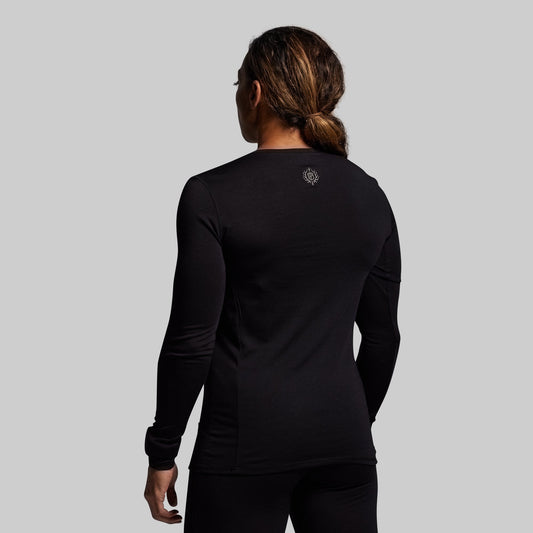 Person wearing a black long-sleeve shirt with a logo on the back against a gray background
