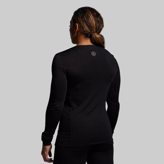 Person wearing a black long-sleeve shirt with a logo on the back against a gray background