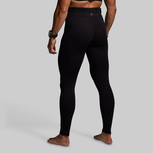 Person wearing black base layer bottoms on a gray background