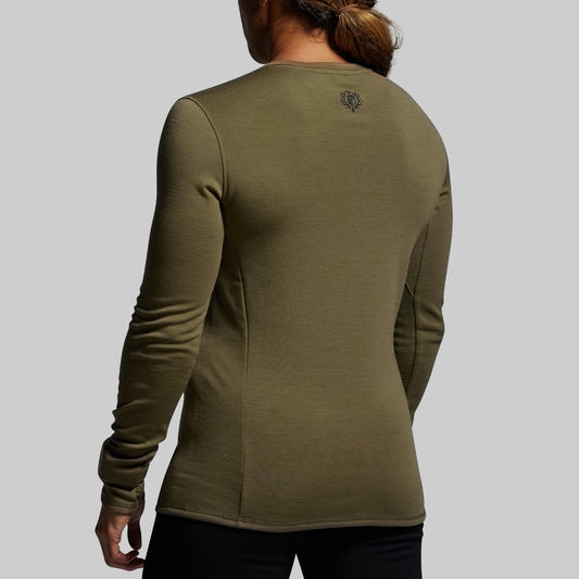 Person wearing a green long-sleeve shirt on a gray background