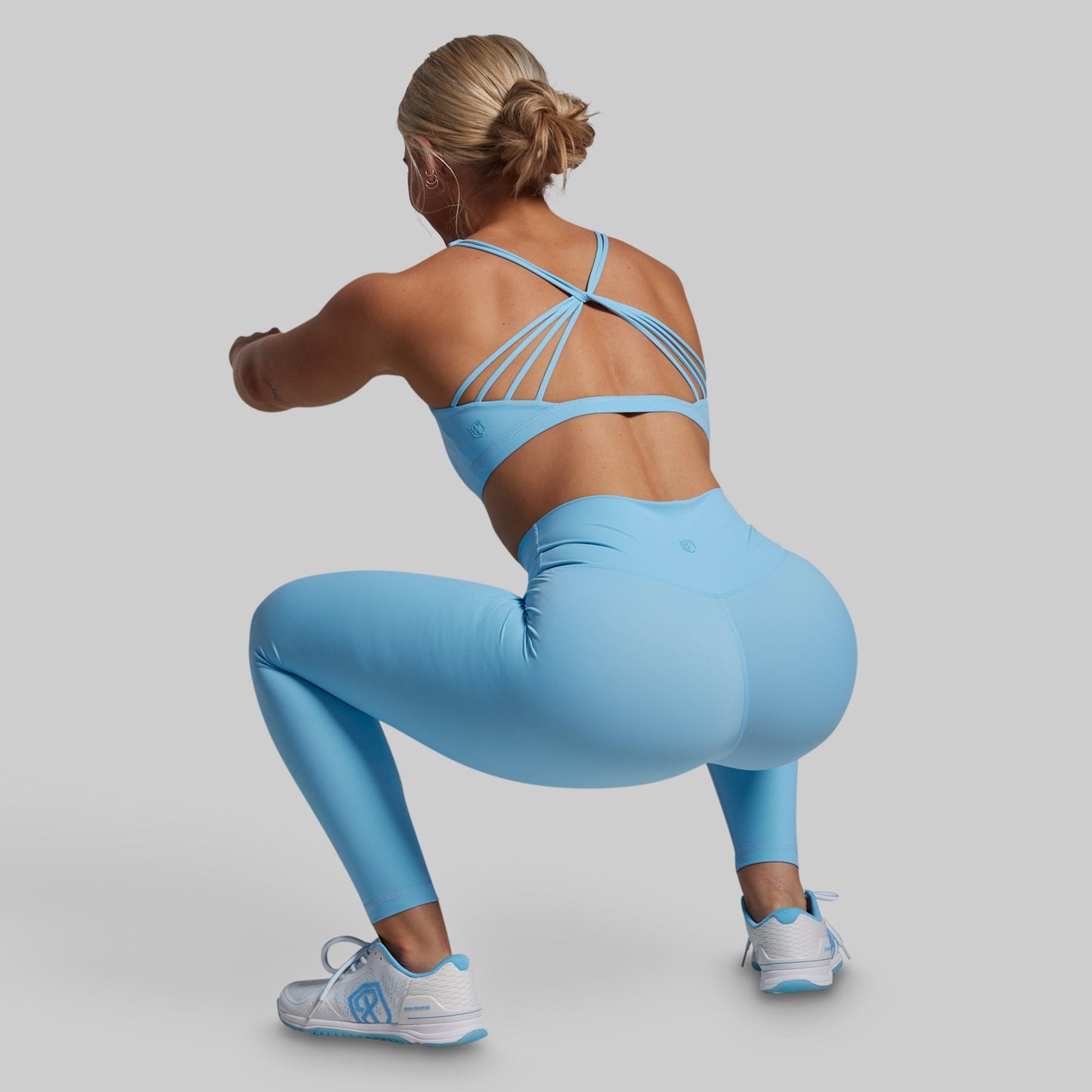 Woman in a blue athletic outfit posing against a gray background