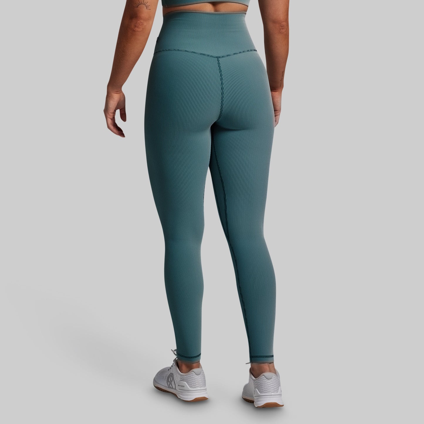Teal leggings worn by a person on a gray background