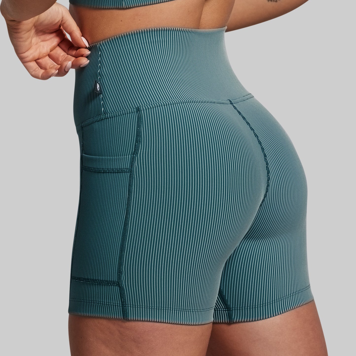 Teal ribbed shorts worn by a person on a gray background
