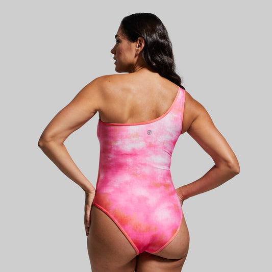 Woman wearing a pink tie-dye swimsuit against a gray background