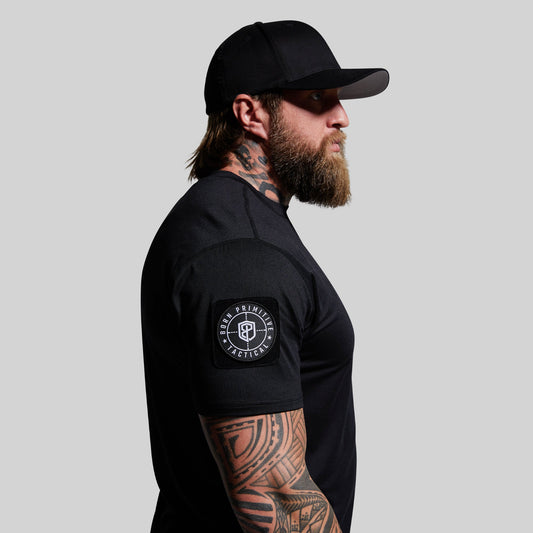 Man wearing a black t-shirt with a logo on the sleeve against a gray background