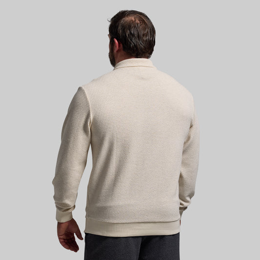 Man wearing a beige textured sweater against a plain background