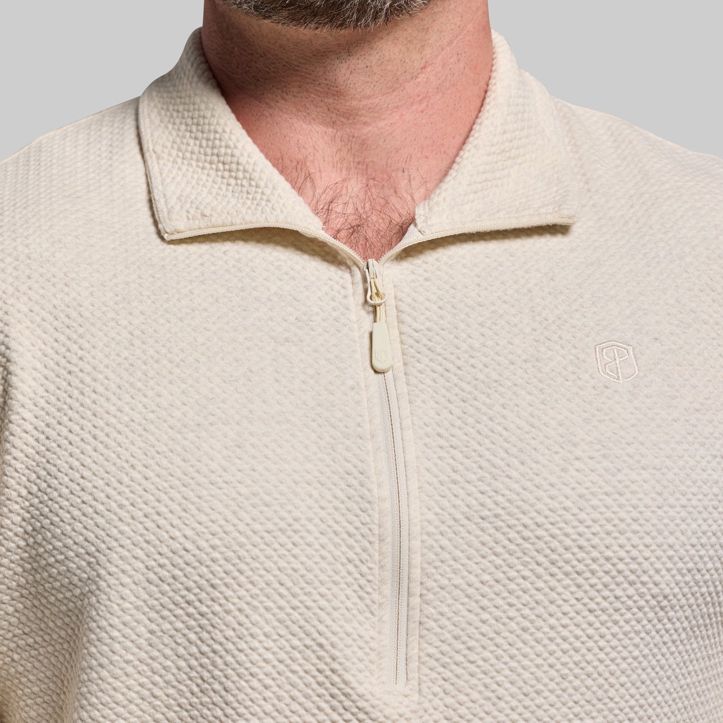 Close-up of a beige pullover with a zipper on a gray background