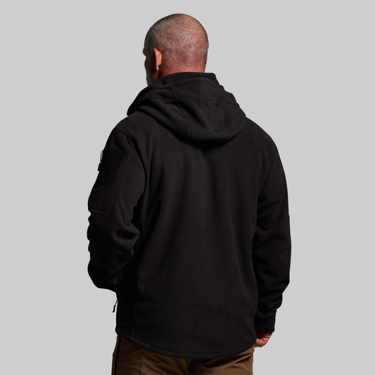 Person wearing a black hoodie from behind on a gray background