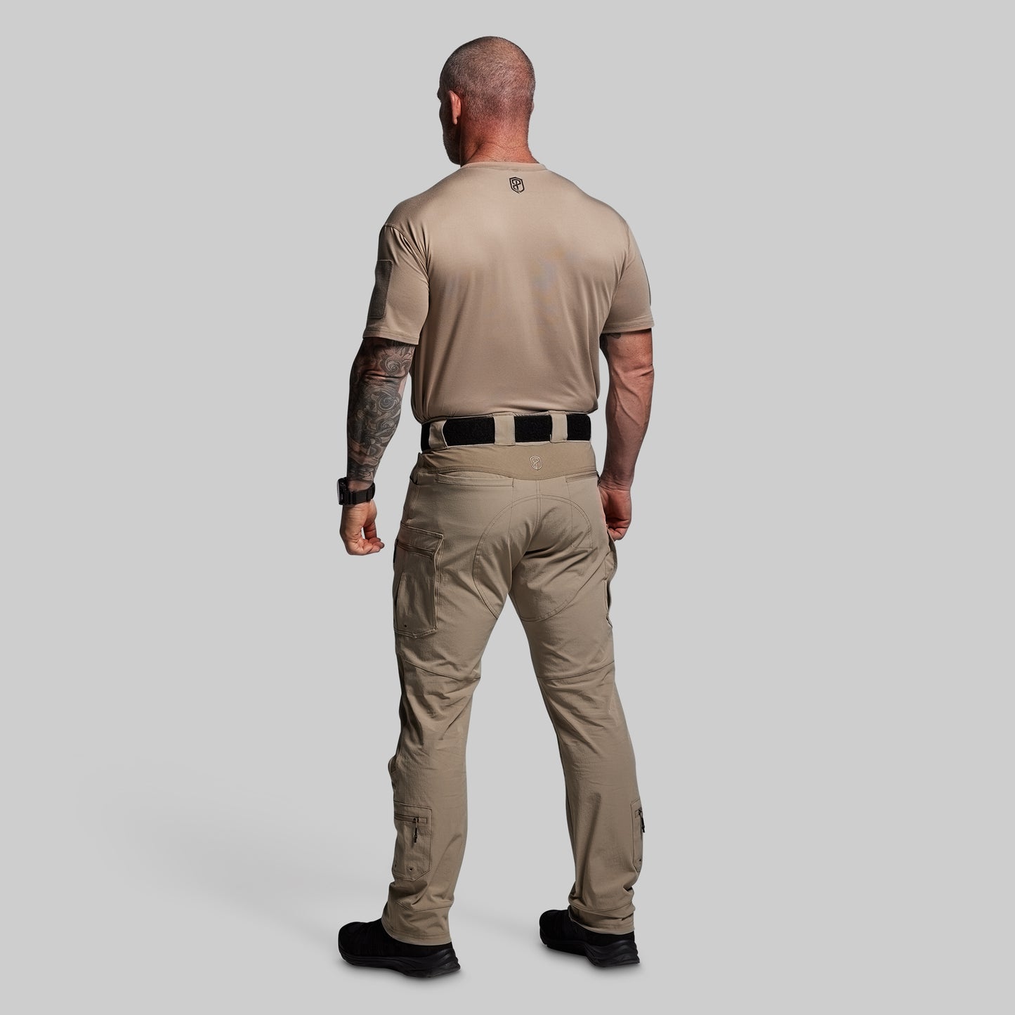 Man wearing a beige tactical outfit on a gray background