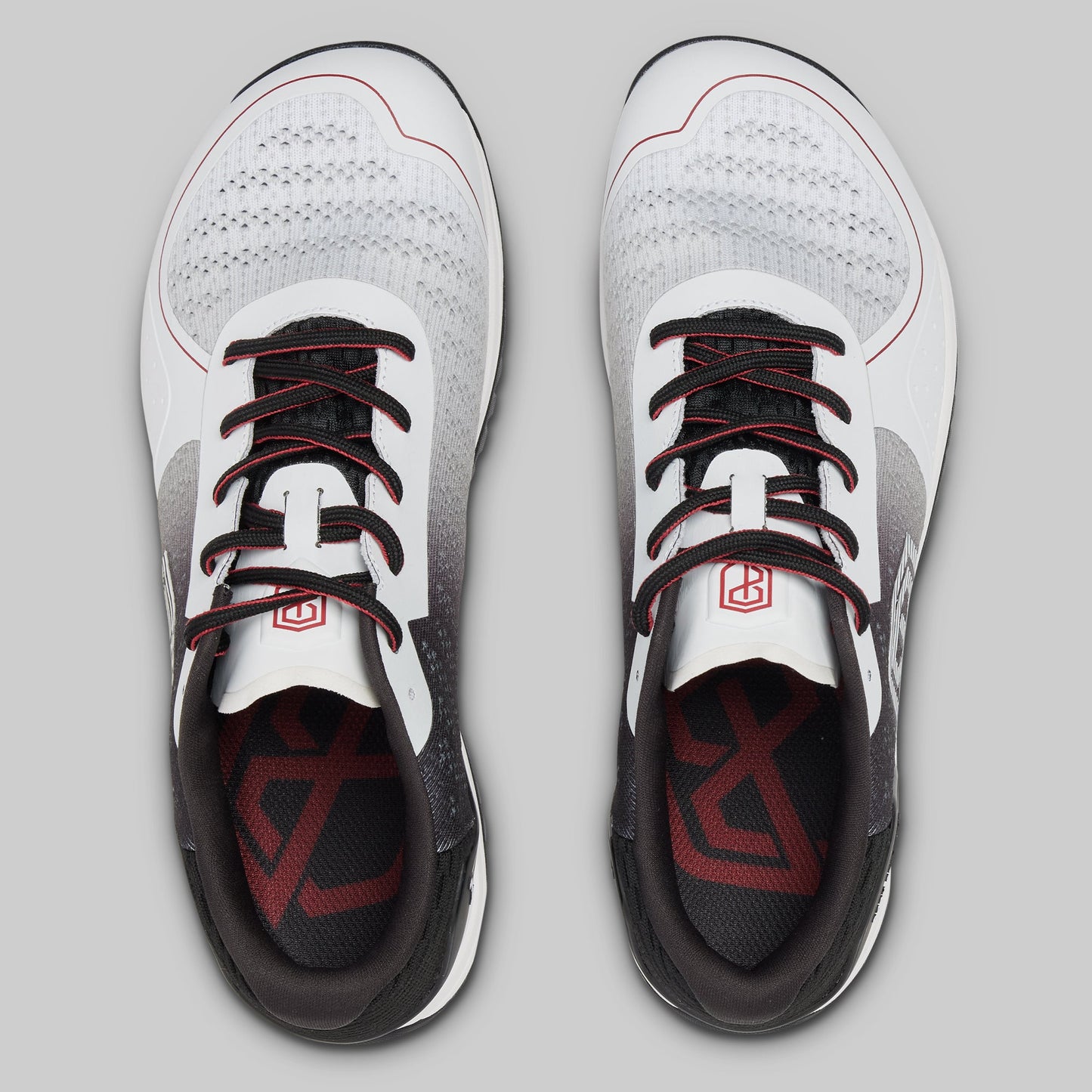 White athletic shoes with black and red accents on a gray background