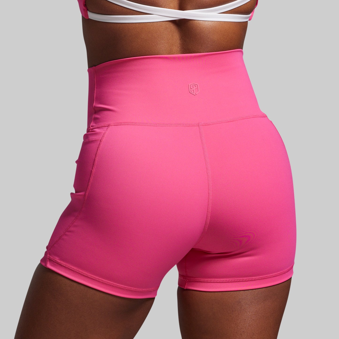 Pink athletic shorts worn by a person on a gray background