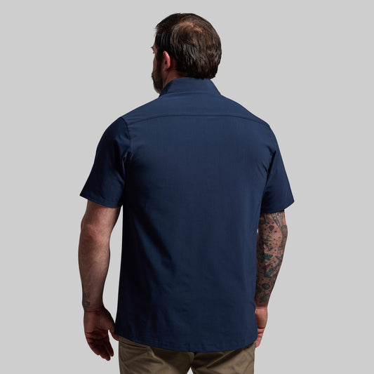 Man wearing a navy blue short-sleeve shirt on a gray background
