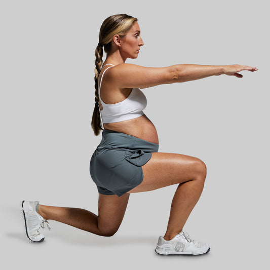 Woman performing a lunge exercise on a plain background