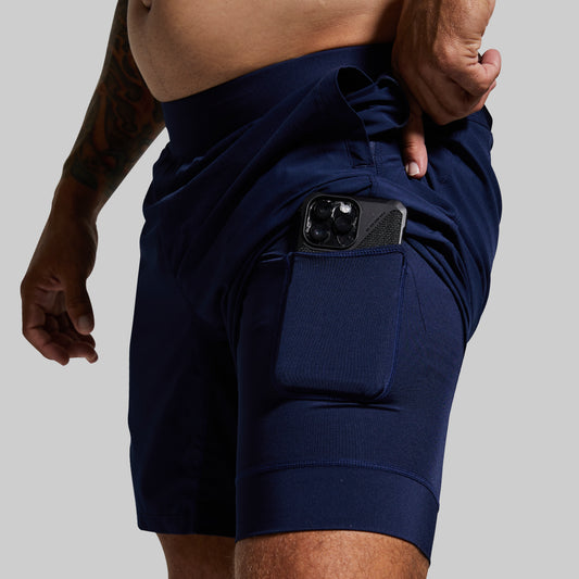 Navy blue athletic shorts with a pocket on a gray background