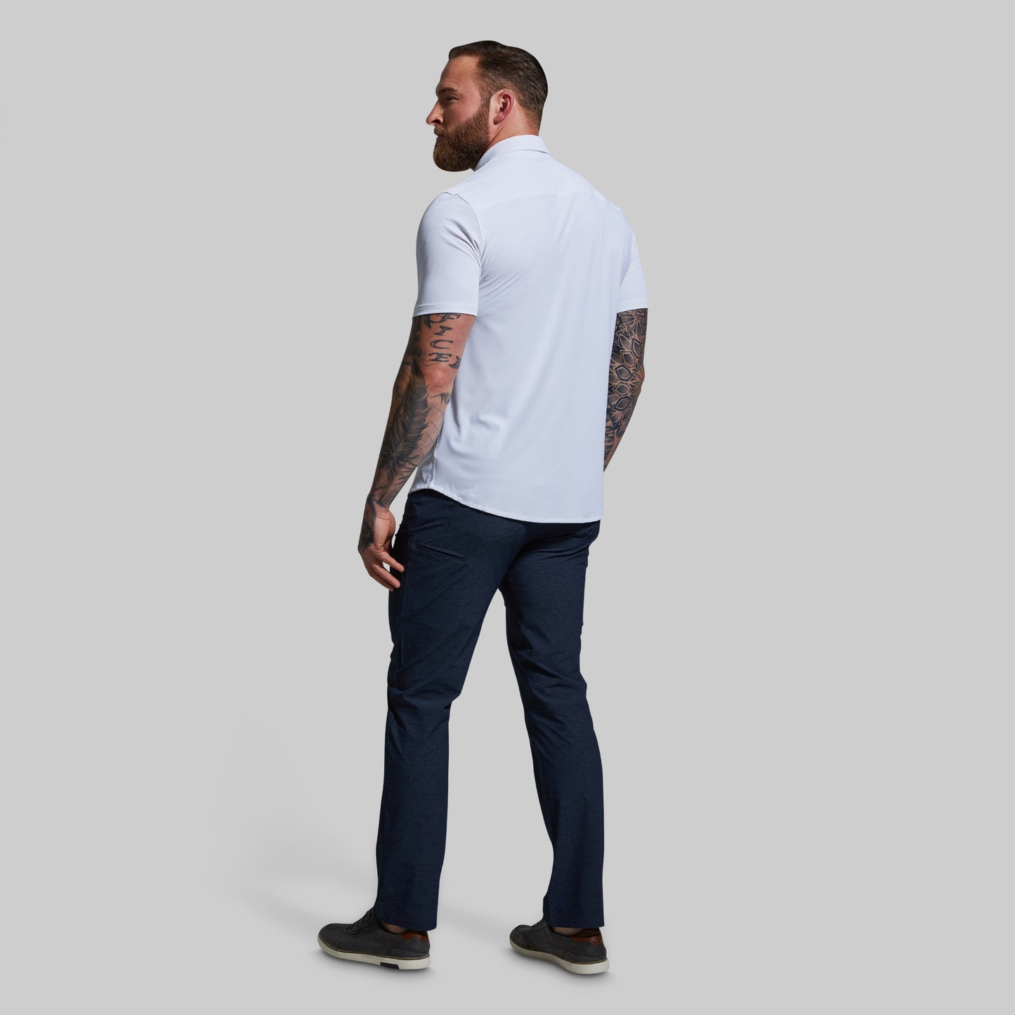Man wearing a white shirt and navy pants on a light gray background