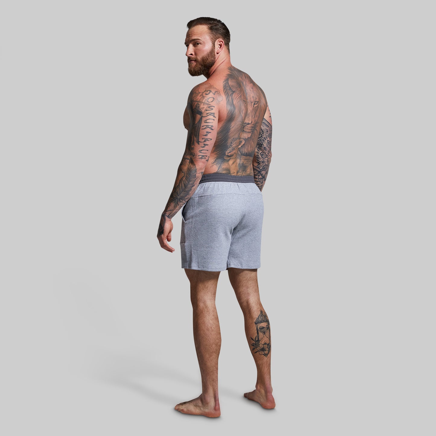 Man wearing gray shorts standing against a plain background