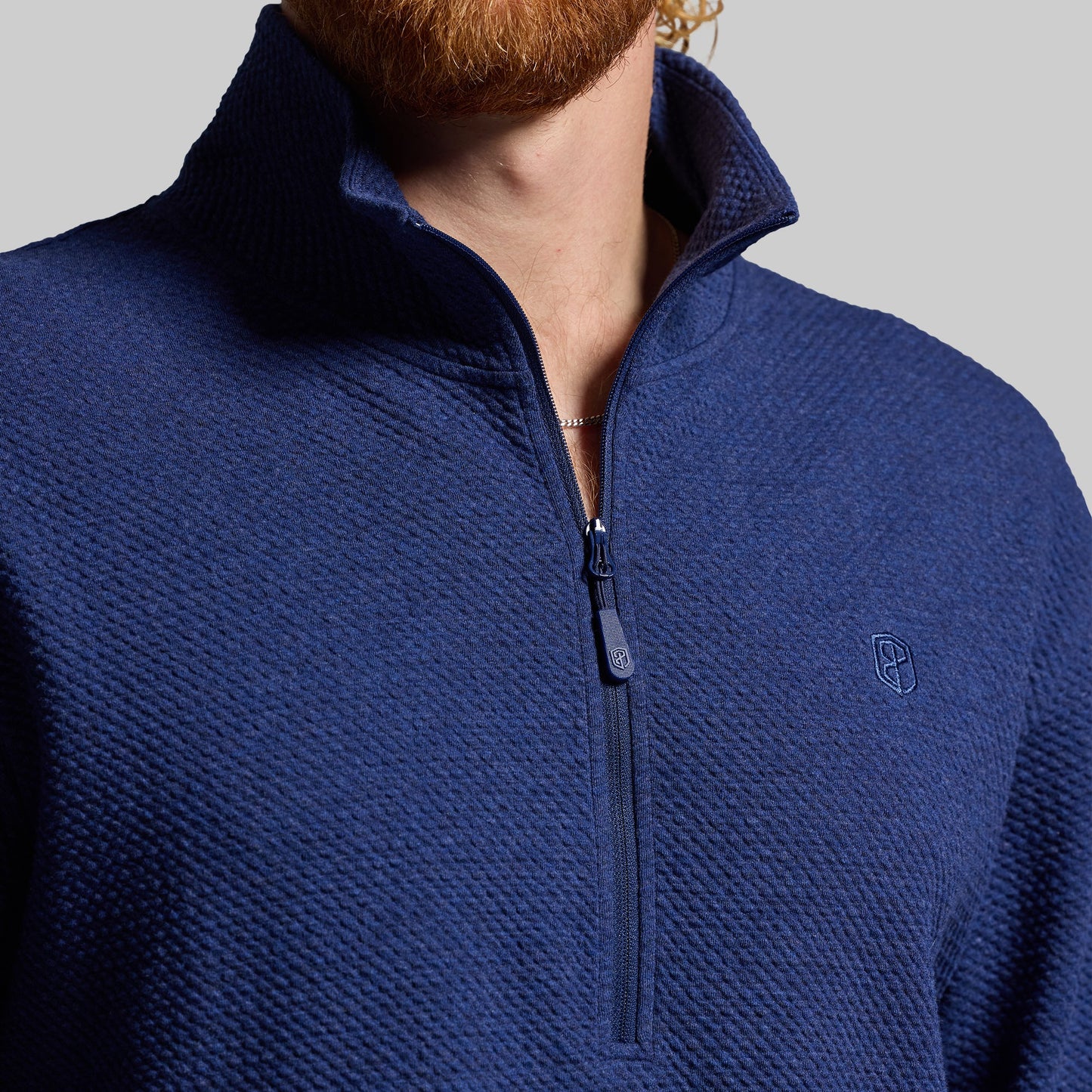 Close-up of blue quarter zip sweatshirt with high collar