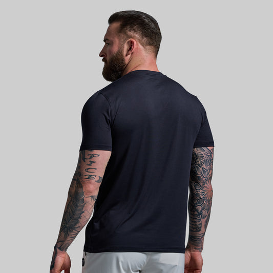 Man wearing a black t-shirt with tattoos on arms against a gray background
