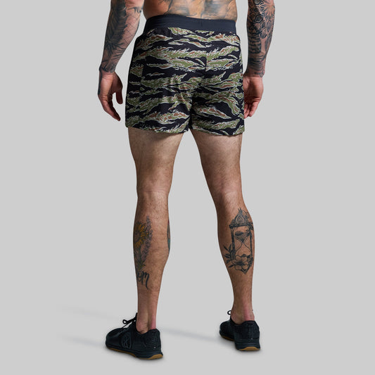 Person wearing camouflage shorts on a plain background