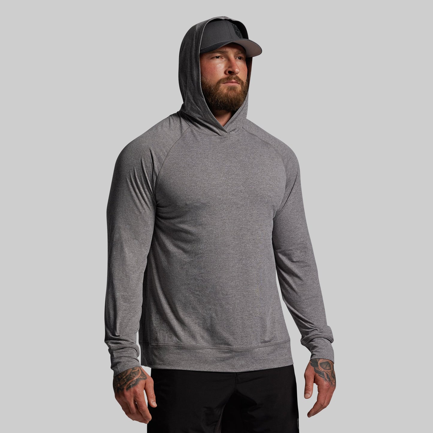 Man wearing a gray hoodie and cap on a light gray background