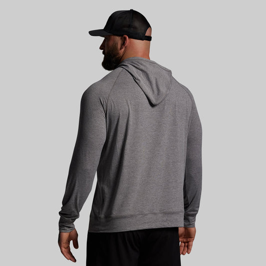Man wearing a gray hoodie and black cap on a light gray background