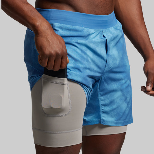 Blue and gray athletic shorts on a person against a gray background