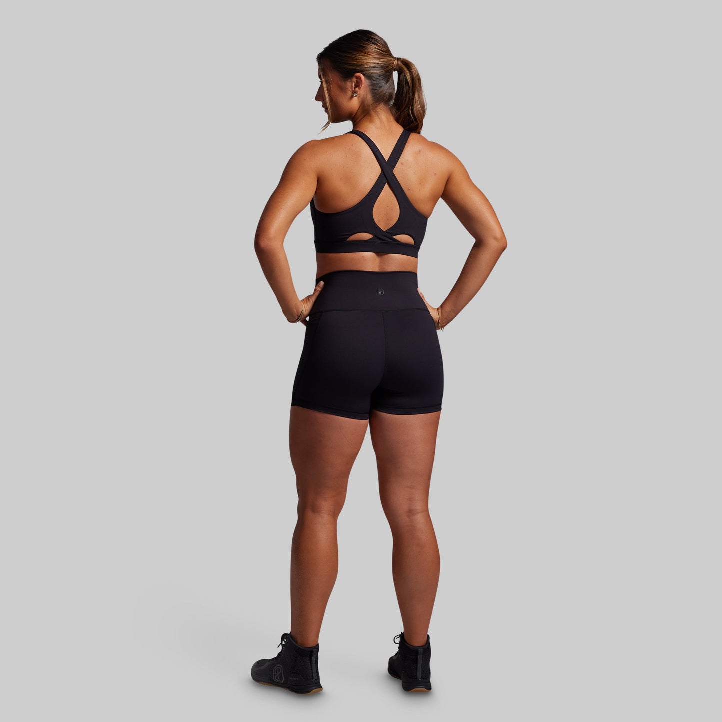 Woman wearing a black sports bra and shorts set on a gray background