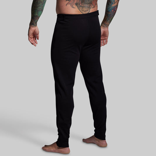 Person wearing black pants on a plain background