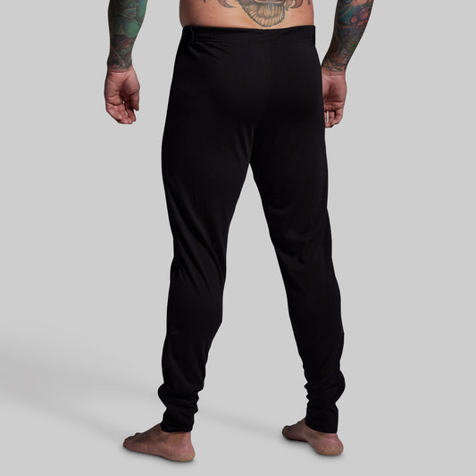 Person wearing black pants on a plain background