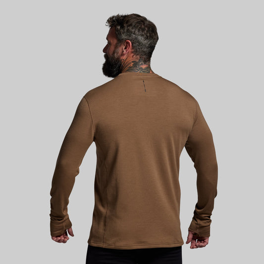 Man wearing a brown long-sleeve shirt against a gray background