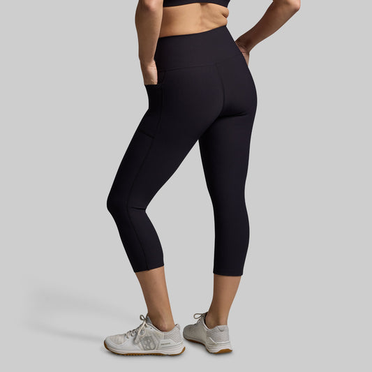 Woman wearing black capri leggings on a gray background