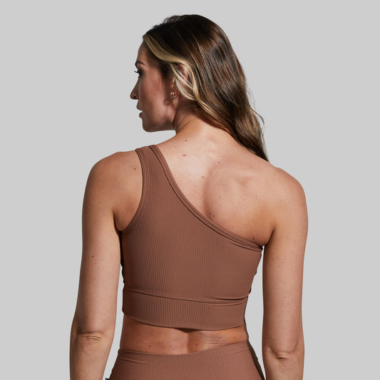 Woman wearing a brown ribbed sports bra against a plain background