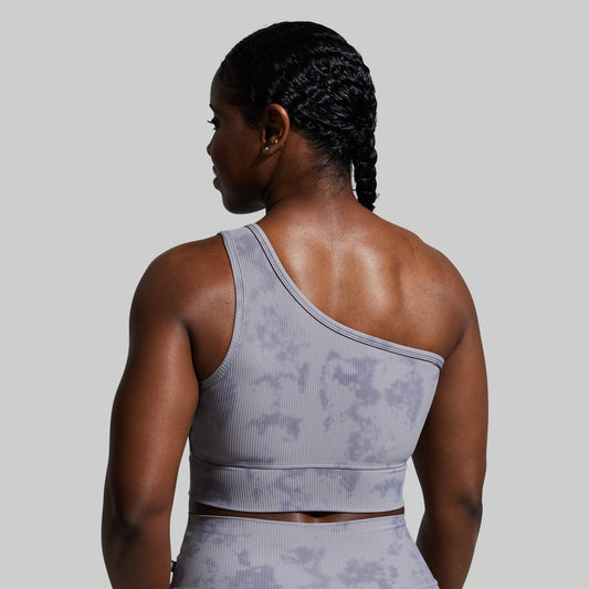 Person wearing a gray sports bra with a subtle pattern on a plain background