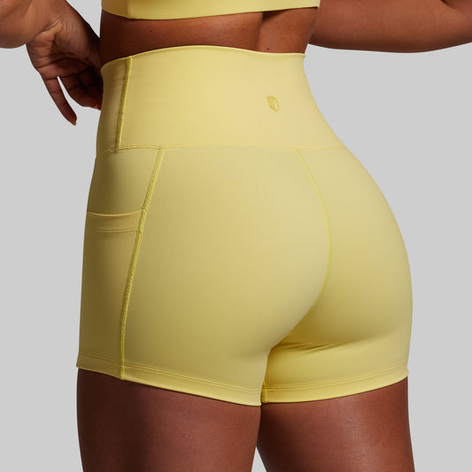 Yellow athletic shorts being worn on a plain background