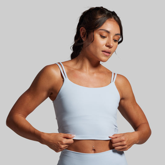 Woman wearing a light blue sports bra against a plain background