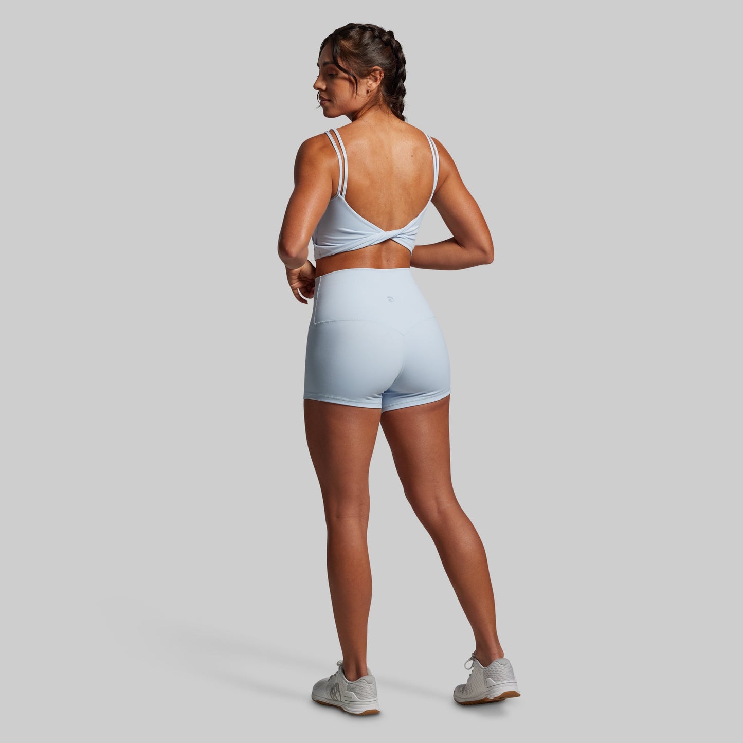 Person wearing a light blue athletic outfit standing with back to camera.