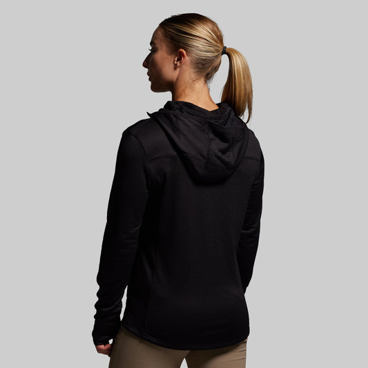 Woman wearing a black hoodie from behind on a gray background