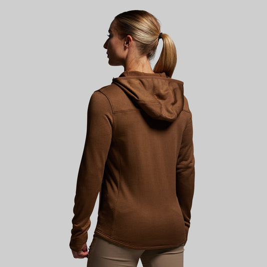 Woman wearing a brown hoodie against a plain background