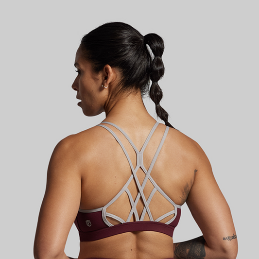 Woman wearing a sports bra with criss-cross straps on a plain background