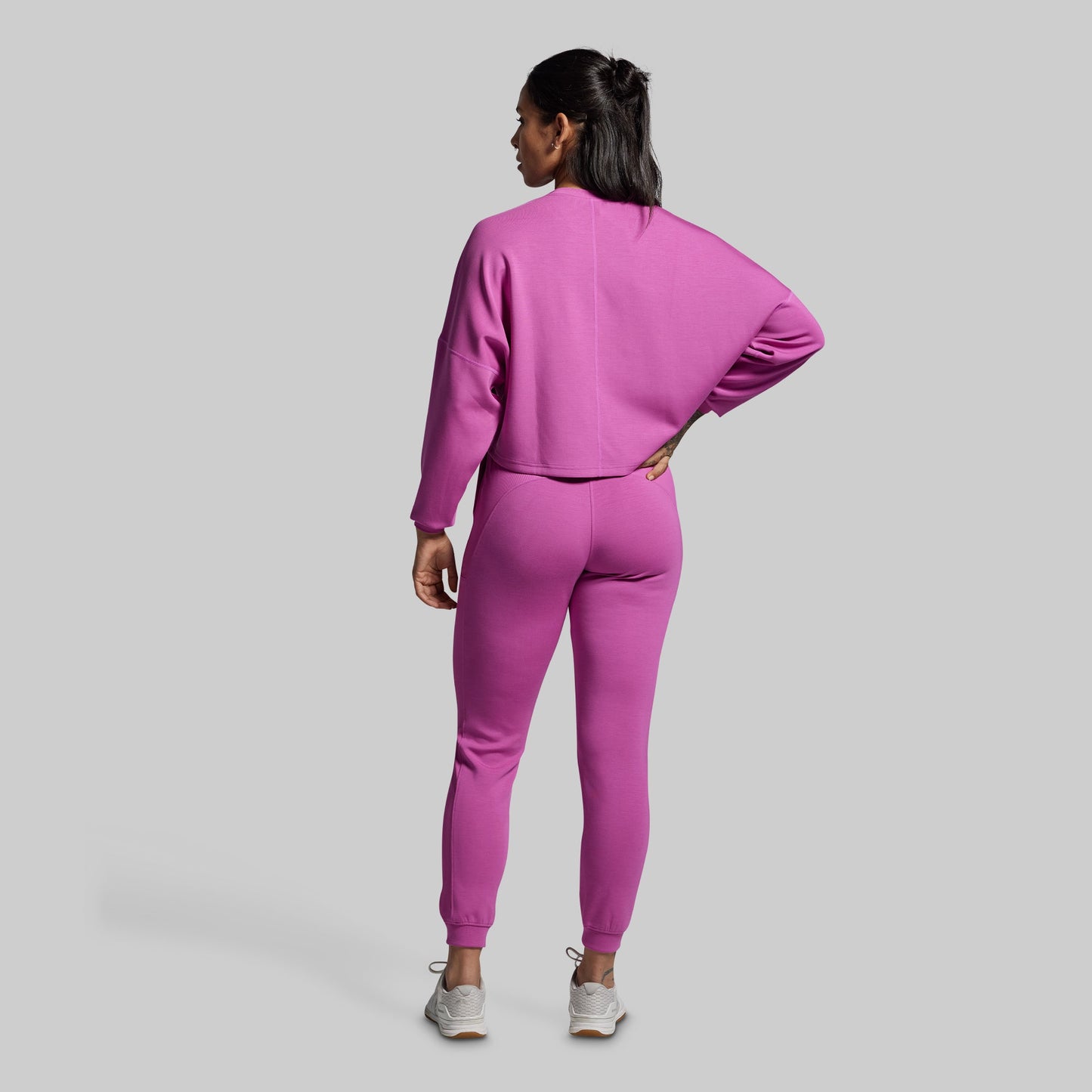 Person wearing a pink tracksuit on a gray background