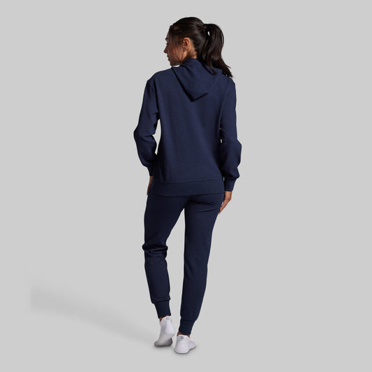 Person wearing a navy tracksuit on a light gray background