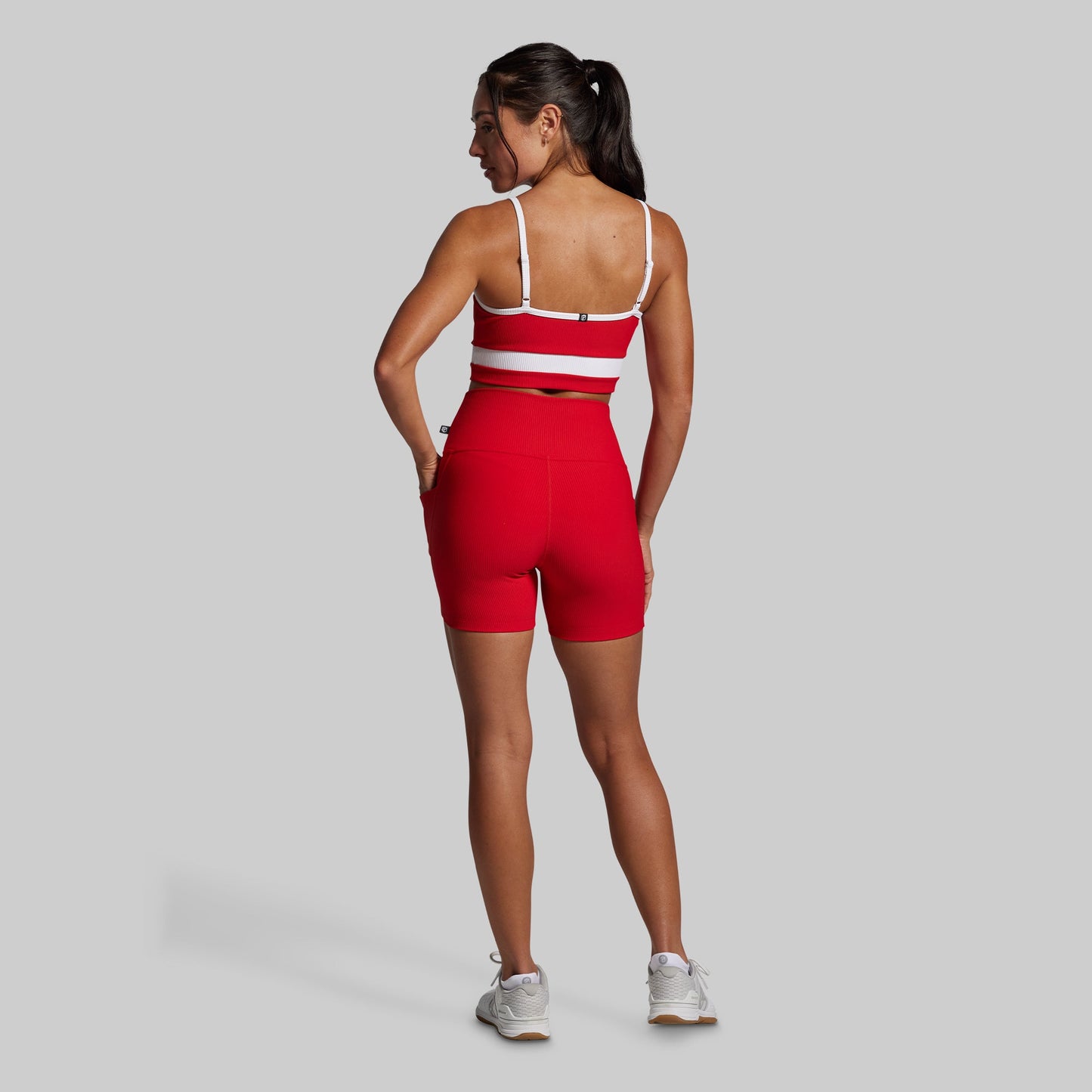 Woman wearing a red and white athletic outfit on a gray background