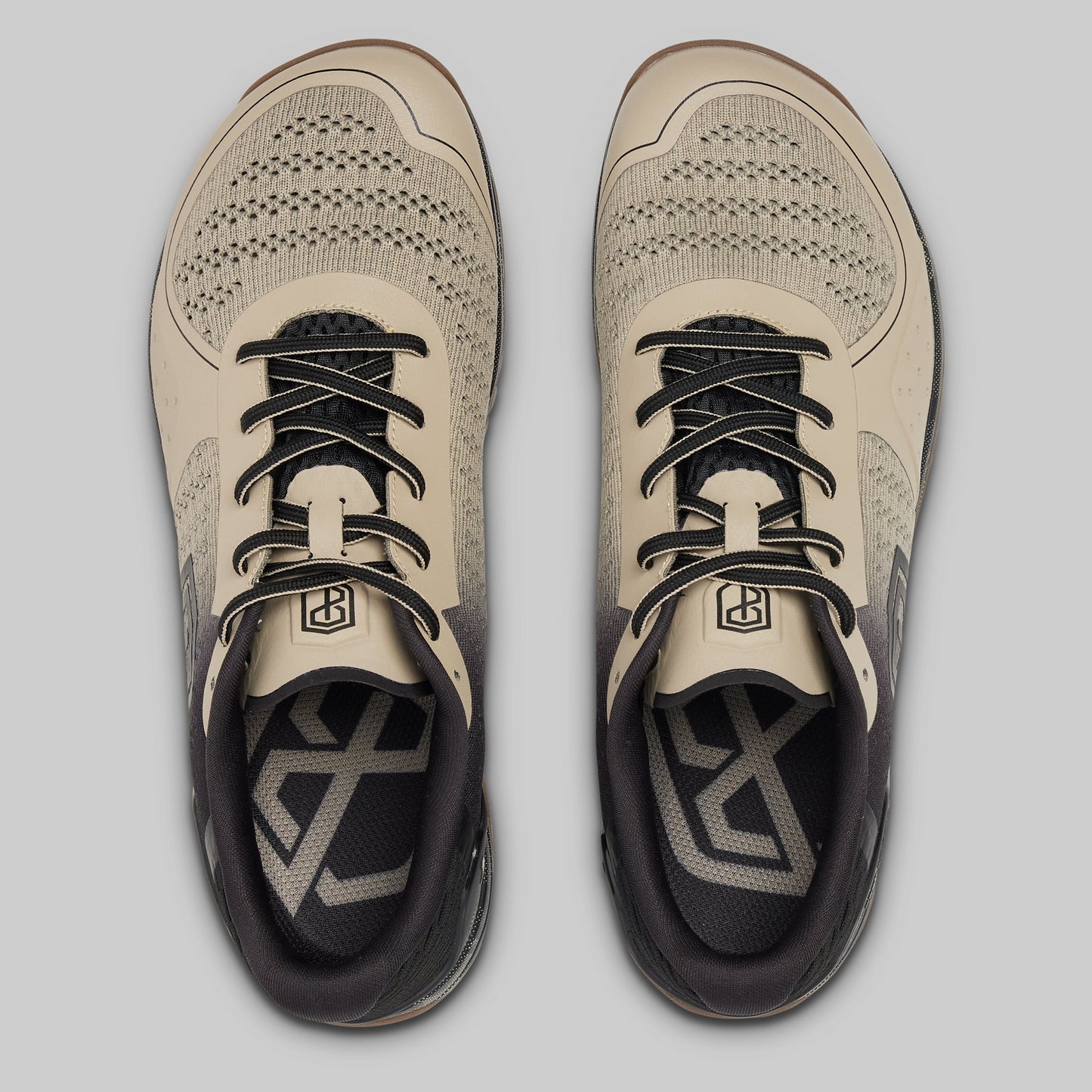 Pair of beige and black athletic shoes on a light gray background