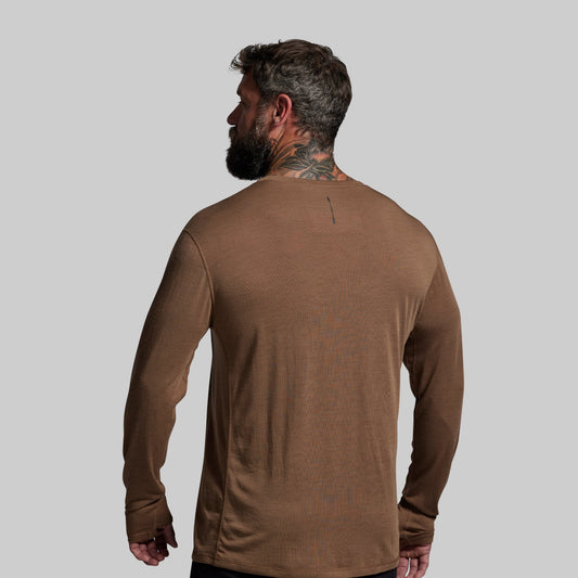 Man wearing a brown long-sleeve shirt against a gray background