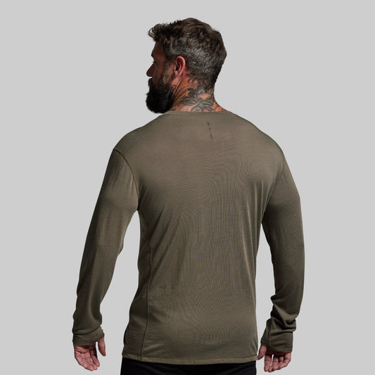 Man wearing a green long-sleeve shirt against a gray background
