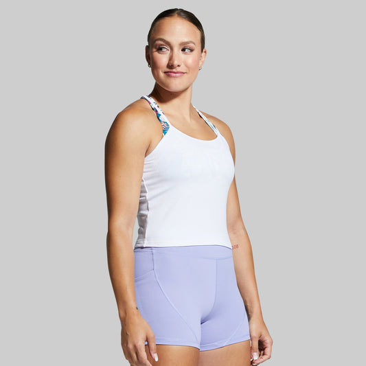 Woman wearing a white tank top and light purple shorts on a gray background