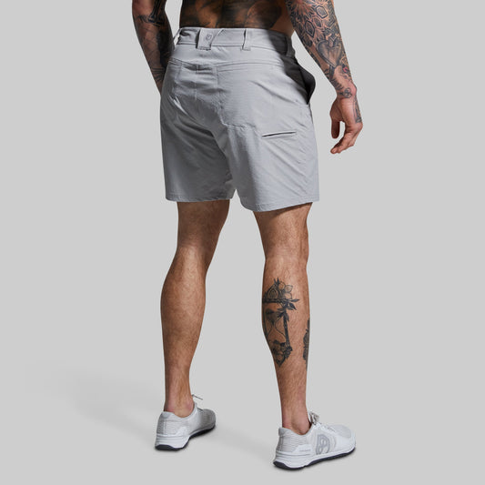 Person wearing light gray shorts on a plain background