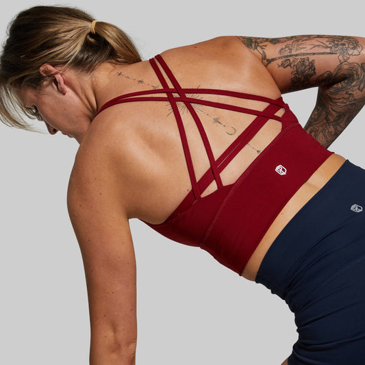 Person wearing a red sports bra and navy leggings on a light gray background