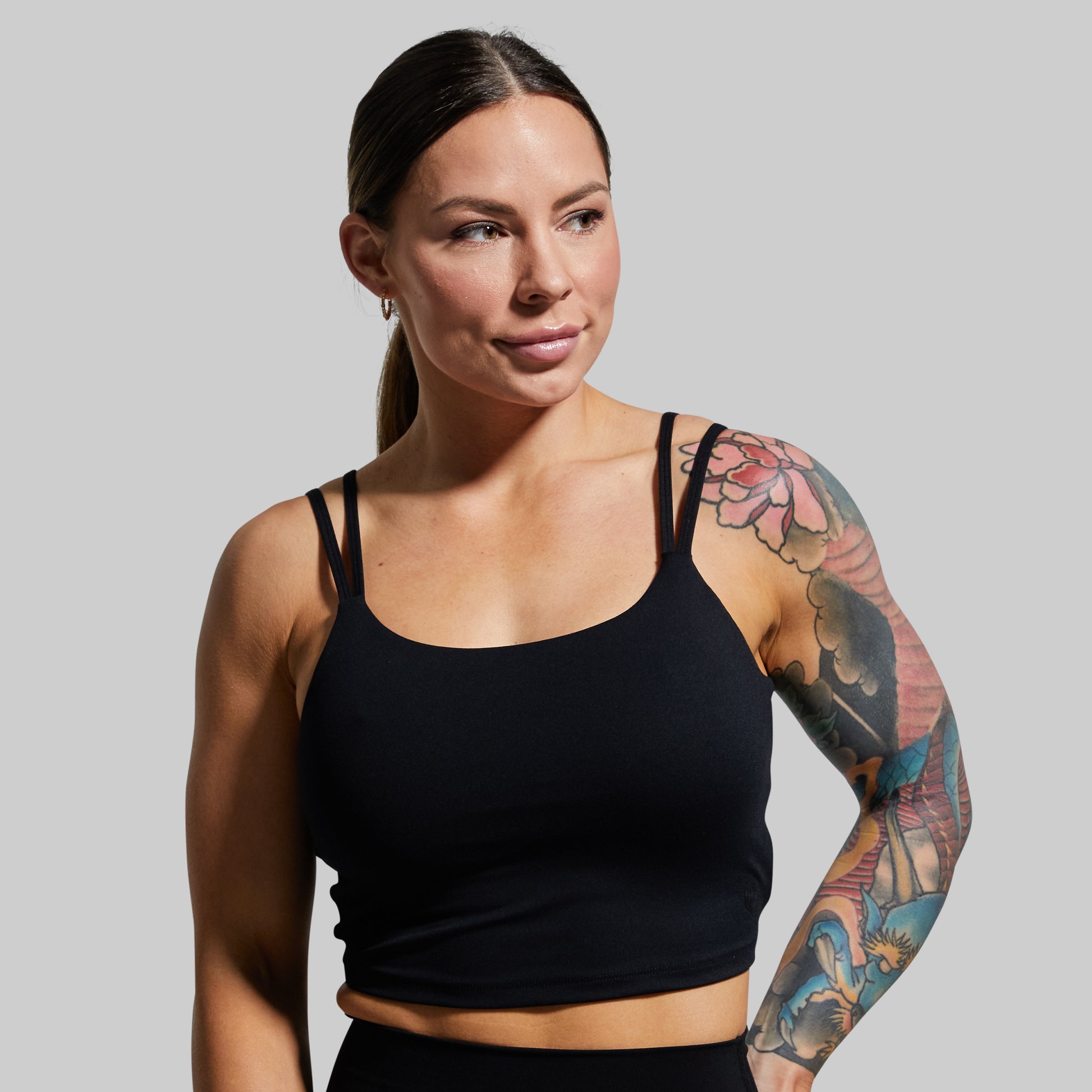 Person wearing a black sports bra with a gray background