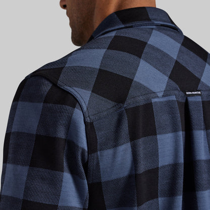 Close-up of a man wearing a blue and black buffalo plaid flannel shirt, showing the back of the neck, collar, and shoulder.